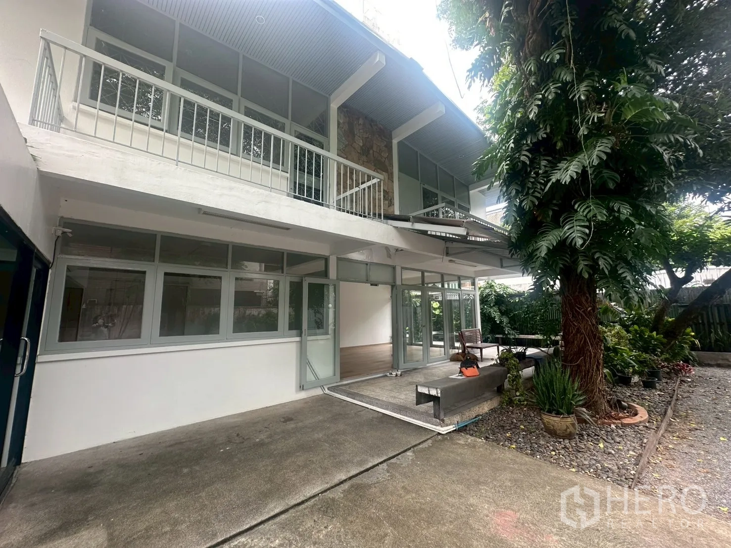 บ้าน ให้เช่าในWatthana, Bangkok - มุมด้านหน้าใกล้ตัวบ้าน มีระเบียง ประตูกระจกเต็มผนัง เฉลียงร่มรื่น และต้นไม้ใหญ่.