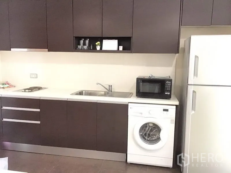 คอนโด ให้เช่าในWatthana, Bangkok - ครัวบิลท์อินตู้สีเข้ม มีอ่างล้างจาน เตาไฟฟ้า เครื่องซักผ้า ไมโครเวฟ และตู้เย็น