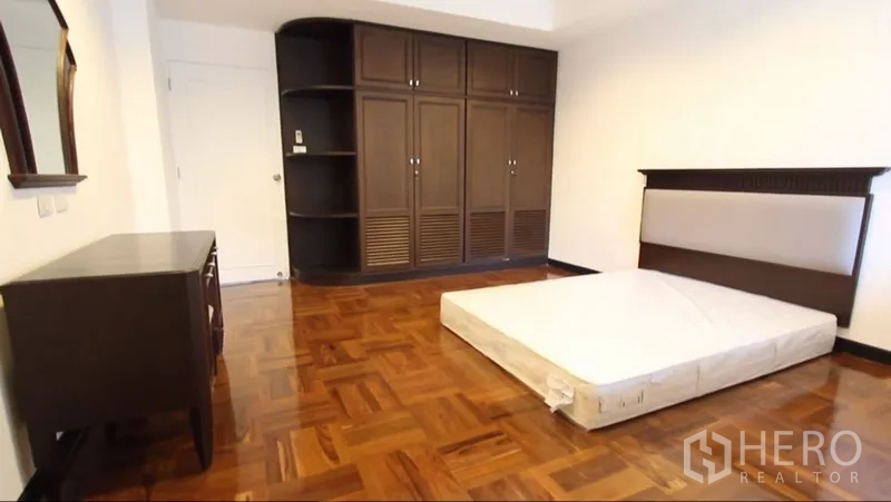 อพาร์ทเมนท์ ให้เช่าในKhlong Toei, Bangkok - ห้องนอนพื้นไม้ปาร์เกต์ ตู้เสื้อผ้าบิวท์อินไม้สีเข้ม และเตียงเตี้ย