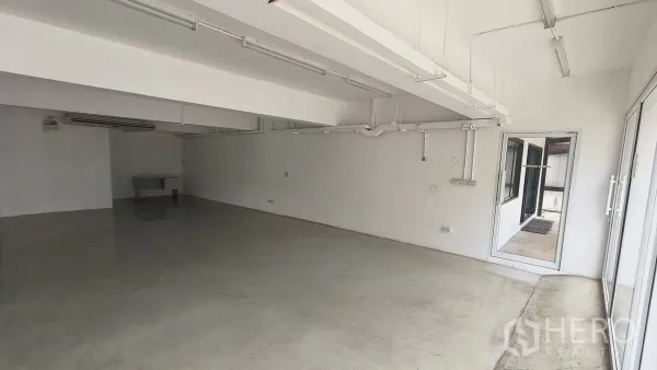 Office Space for rent in Khlong Toei, Bangkok - Office area with exposed ceiling services and a doorway leading outside.