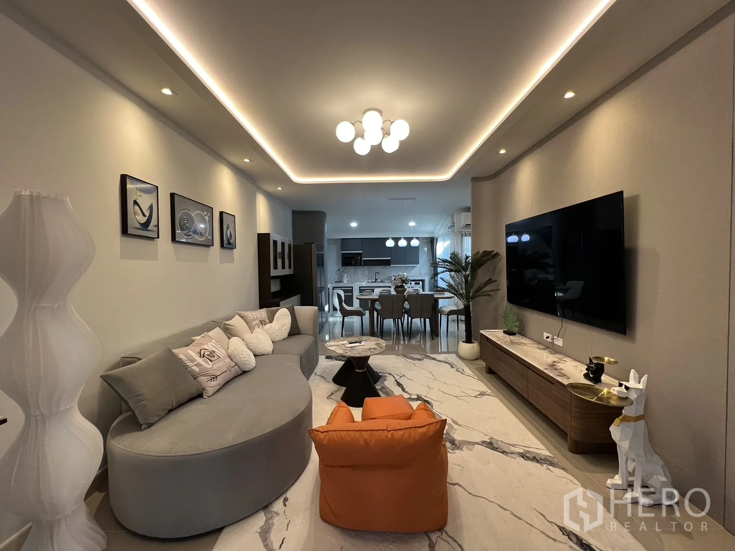 Townhouse for rent in Bang Phli, Samut Prakan - Long view of the lounge toward the kitchen with LED ceiling detail and wall art.