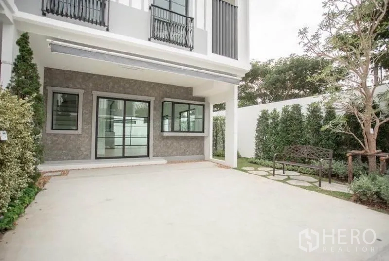 Townhouse for rent in Bang Phli, Samut Prakan - Spacious covered carport and patio with sliding glass doors and garden bench.