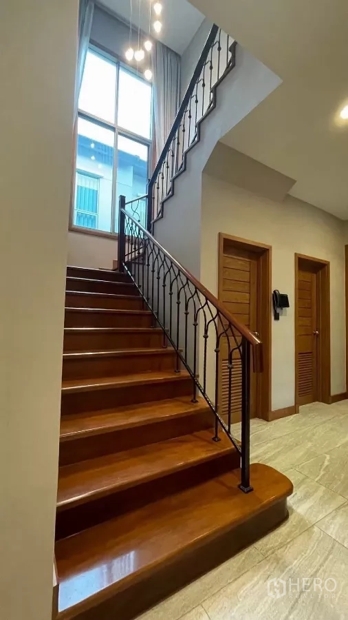 Detached House for rent in Prawet, Bangkok - Entry staircase with wrought-iron balustrade and double-height window.