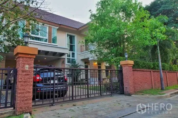 独立式住宅 出租或出售在Pak Kret, Nonthaburi - 两层独栋住宅，带电动门车道、车棚与成树环绕。