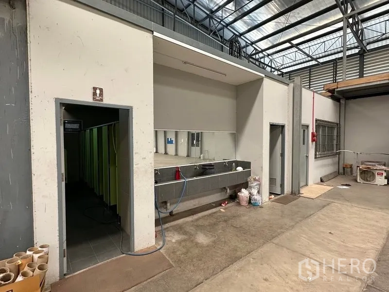 工厂 出售在Phra Nakhon Si Ayutthaya - 厂房内部服务区，配不锈钢洗手台、卫生间与高挑钢结构屋顶。