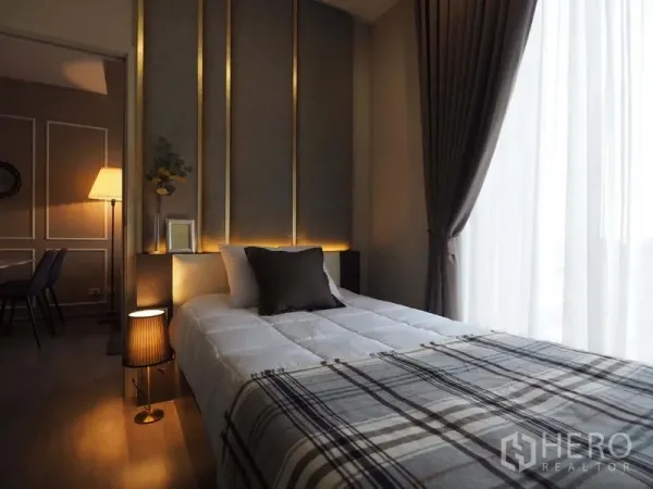 คอนโด ให้เช่าในKhlong San, Bangkok - ห้องนอนหัวเตียงบุผ้า ไฟสลัว และหน้าต่างสูงพร้อมม่านโปร่ง