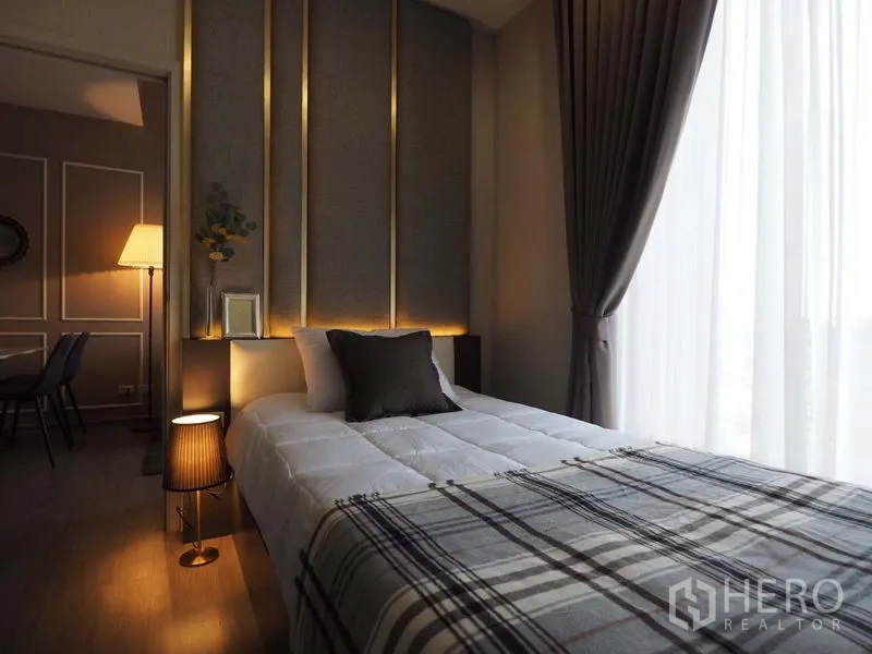 คอนโด ให้เช่าในKhlong San, Bangkok - ห้องนอนหัวเตียงบุผ้า ไฟสลัว และหน้าต่างสูงพร้อมม่านโปร่ง