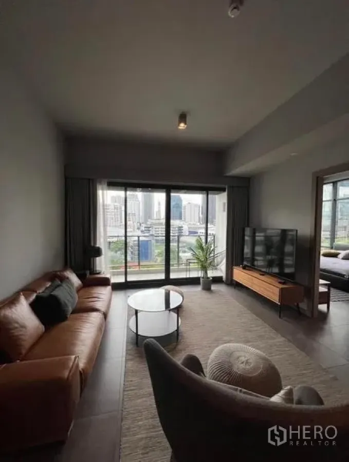 Condominium for rent in Watthana, Bangkok - Modern living room with leather sofa, TV console and balcony city view.