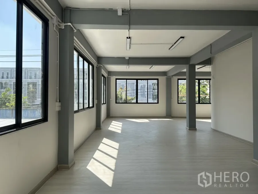 办公空间 出租在Phra Khanong, Bangkok - 采光充足的开放式办公楼层，大片黑框窗、灰色梁与浅色地板。