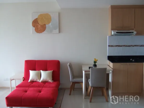 คอนโด ให้เช่าในKhlong Toei, Bangkok - ห้องนั่งเล่นสว่าง โซฟาแดง โต๊ะกินข้าวสองที่ และครัวขนาดกะทัดรัด