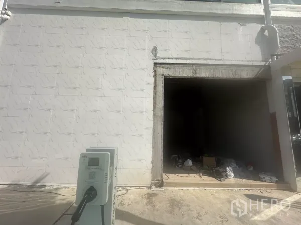 Retail Space for rent in Bang Na, Bangkok - Shopfront opening under construction on a tiled exterior wall with an EV charging station visible in the foreground.