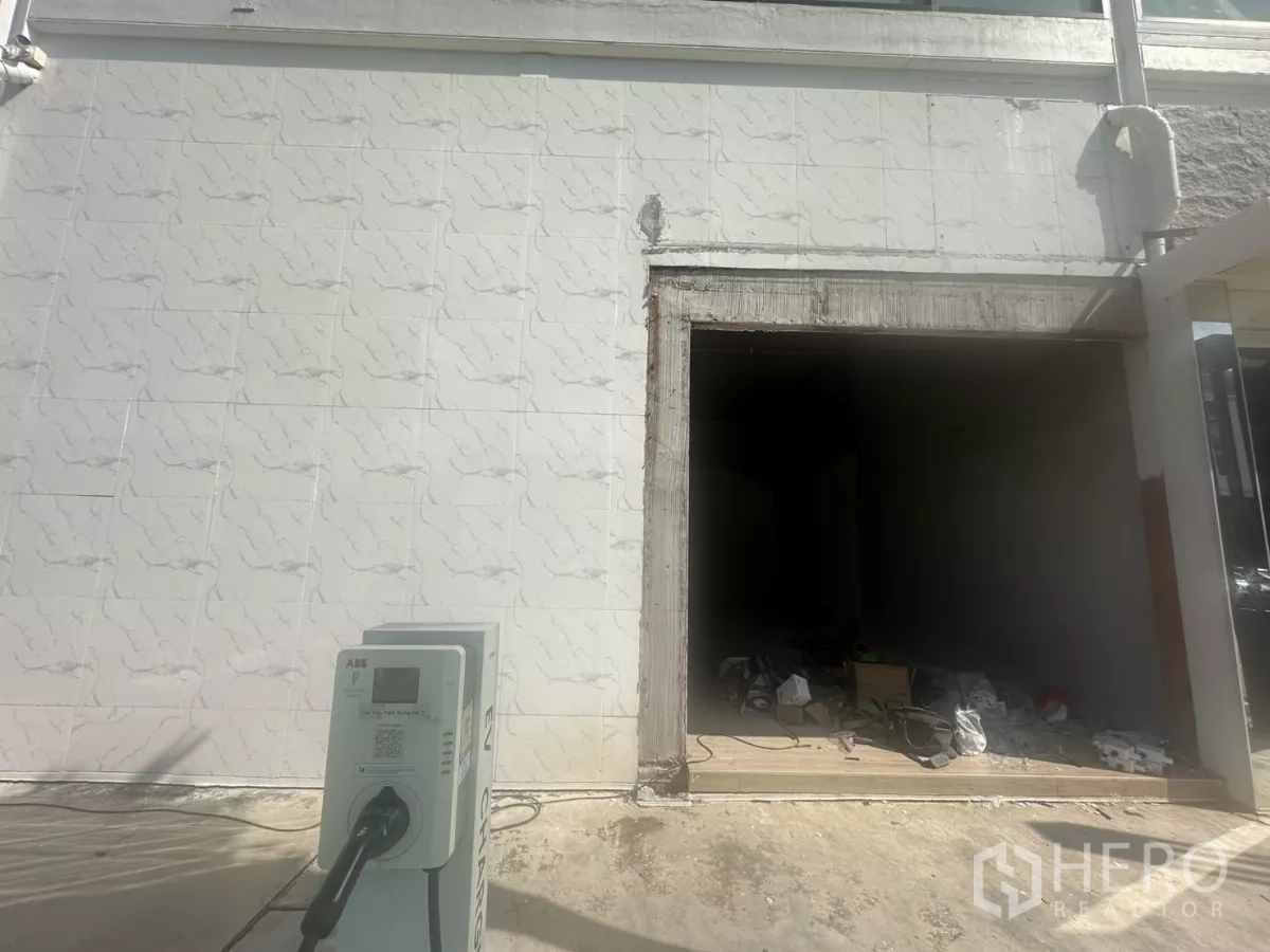 Retail Space for rent in Bang Na, Bangkok - Shopfront opening under construction on a tiled exterior wall with an EV charging station visible in the foreground.