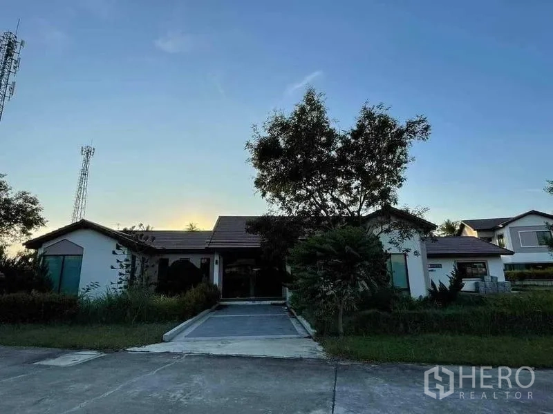 คลังสินค้า ขายในChon Buri - อาคารสำนักงานหรือที่พักแบบชั้นเดียว มีทางรถเข้าพร้อมต้นไม้ใหญ่ยามเย็น