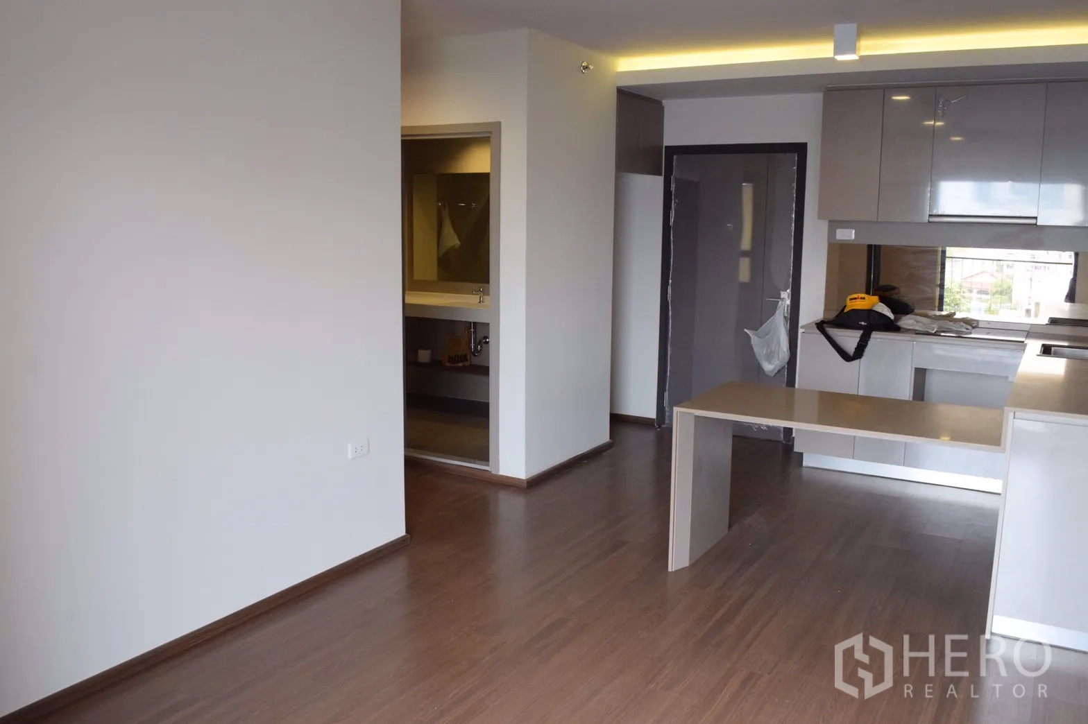 คอนโด ให้เช่าในPhra Khanong, Bangkok - พื้นที่นั่งเล่นแบบโอเพ่นพร้อมพื้นลามิเนตและครัวบิวท์อินมีเคาน์เตอร์เพนนินซูลา