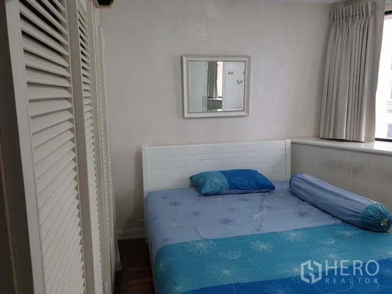 公寓 出租在Khlong Toei, Bangkok - 次卧采光良好，白色床架、蓝色床品与百叶衣柜。