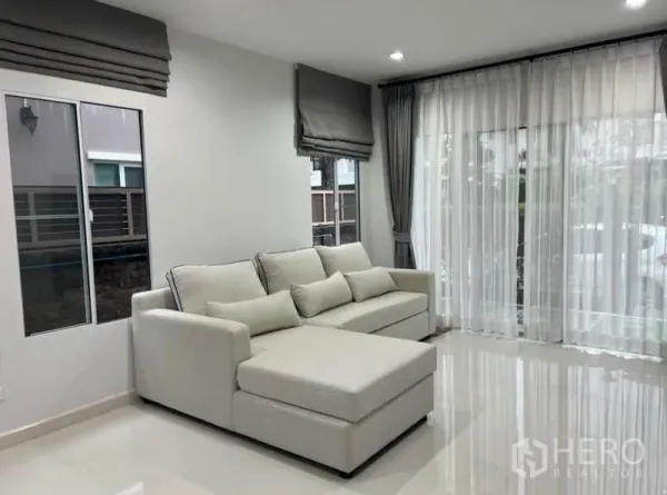 独立式住宅 出租在Suan Luang, Bangkok - 客厅一角，米色沙发与大推拉玻璃门