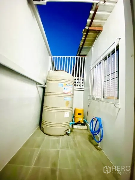 联排别墅 出租在Prawet, Bangkok - 带顶后勤区，设有蓄水罐、水泵与水管，旁有窗护栏。