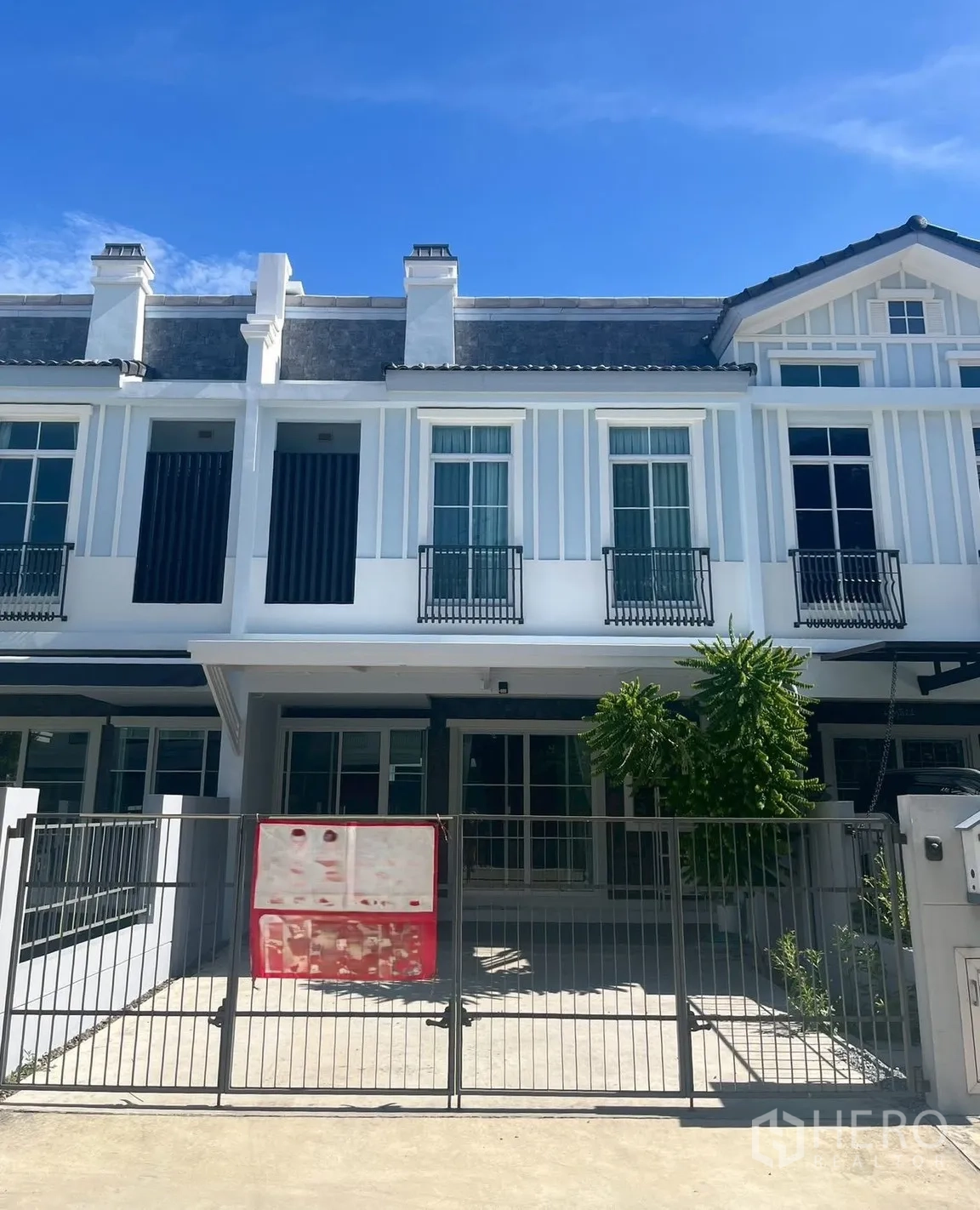 ทาวน์เฮาส์ for rent in Prawet, Bangkok - ด้านหน้าทาวน์เฮ้าส์สองชั้นสมัยใหม่พร้อมรั้วและทางจอดรถ.