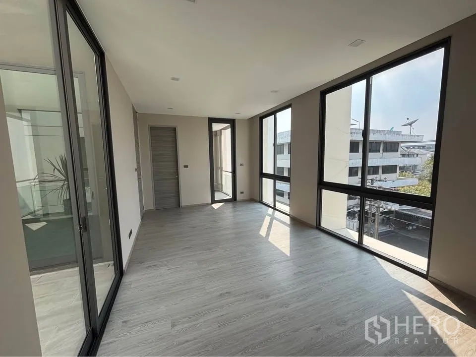 Home Office for rent or sale in Suan Luang, Bangkok - Bright office room with floor-to-ceiling windows and wood-look flooring.