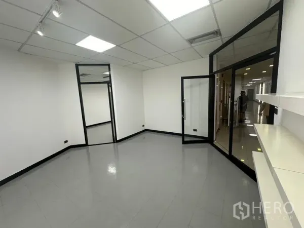 Office Space for rent - Bright reception or meeting room with glass entrance, white walls, tiled floor and drop ceiling lights in a Bangkok office.