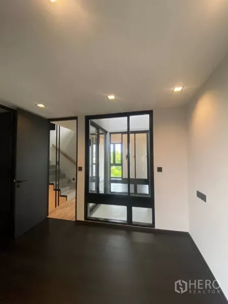 ทาวน์เฮาส์ ให้เช่าในHuai Khwang, Bangkok - ห้องพื้นสีเข้มพร้อมผนังกระจก มองเห็นทางขึ้นบันได.