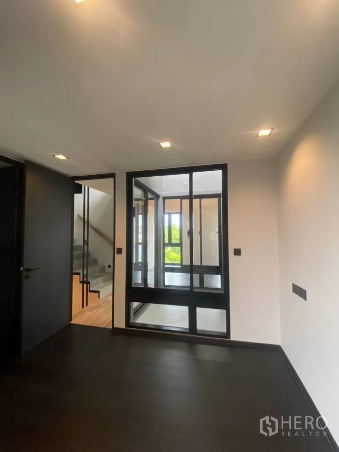 ทาวน์เฮาส์ ให้เช่าในHuai Khwang, Bangkok - ห้องพื้นสีเข้มพร้อมผนังกระจก มองเห็นทางขึ้นบันได.