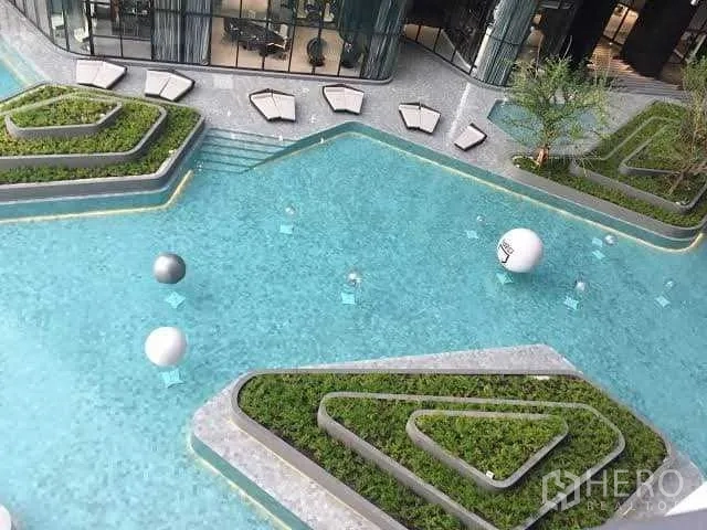 Condominium for sale in Bang Rak, Bangkok - Large swimming pool with geometric planters and seating areas in a contemporary residence.