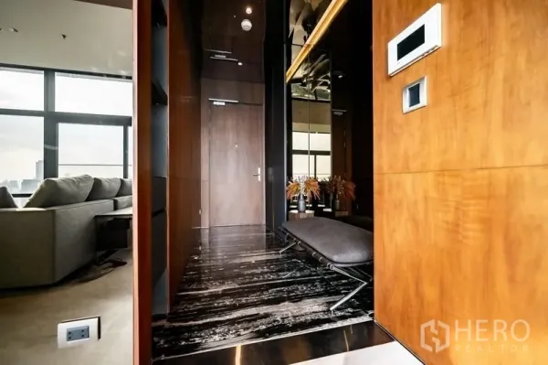 公寓 出售在Ratchathewi, Bangkok - 入口走廊，深色大理石地面与木饰面，设长凳通向客厅。