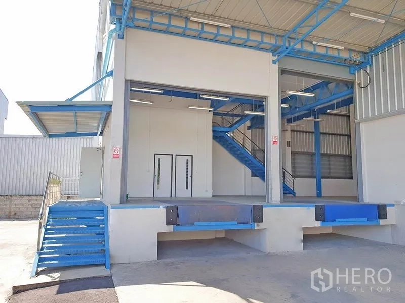 คลังสินค้า ให้เช่าในLat Krabang, Bangkok - ท่าขนถ่ายยกระดับพร้อมประตูม้วนและบันไดเหล็กสีน้ำเงินอยู่ใต้ชายคาหน้าโกดัง