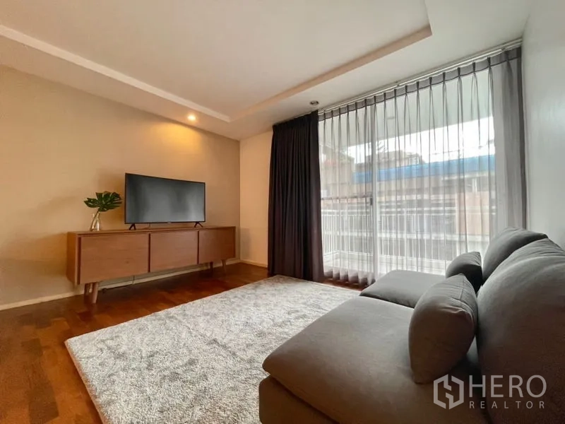 คอนโด ให้เช่าหรือขายในKhlong Toei, Bangkok - มุมนั่งเล่นพร้อมโซฟา ตู้วางทีวี และหน้าต่างเต็มบานพร้อมผ้าม่าน