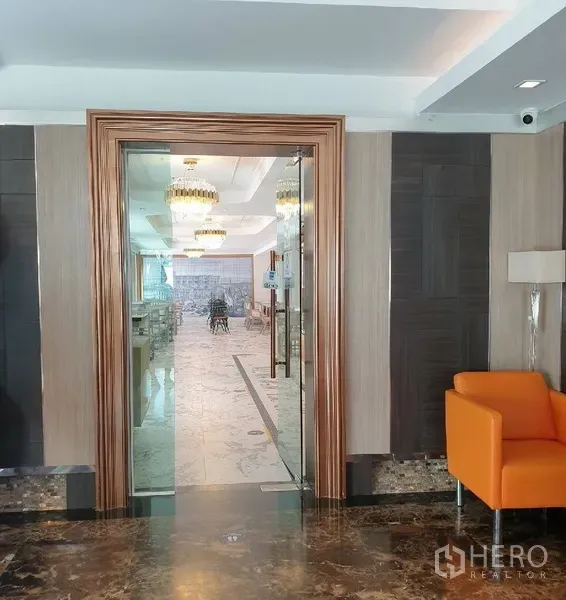 零售空间 出租在Khlong Toei, Bangkok - 木框玻璃门入口，通向铺内明亮的大理石地面与水晶吊灯的用餐区。