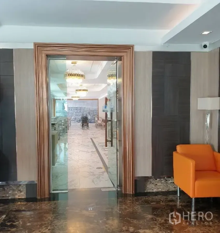 零售空间 出租在Khlong Toei, Bangkok - 木框玻璃门入口，通向铺内明亮的大理石地面与水晶吊灯的用餐区。