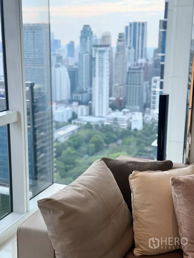 คอนโด ให้เช่าในPathum Wan, Bangkok - โซฟาติดผนังกระจกสูง เห็นวิวอาคารใจกลางเมืองและพื้นที่สีเขียวด้านล่าง
