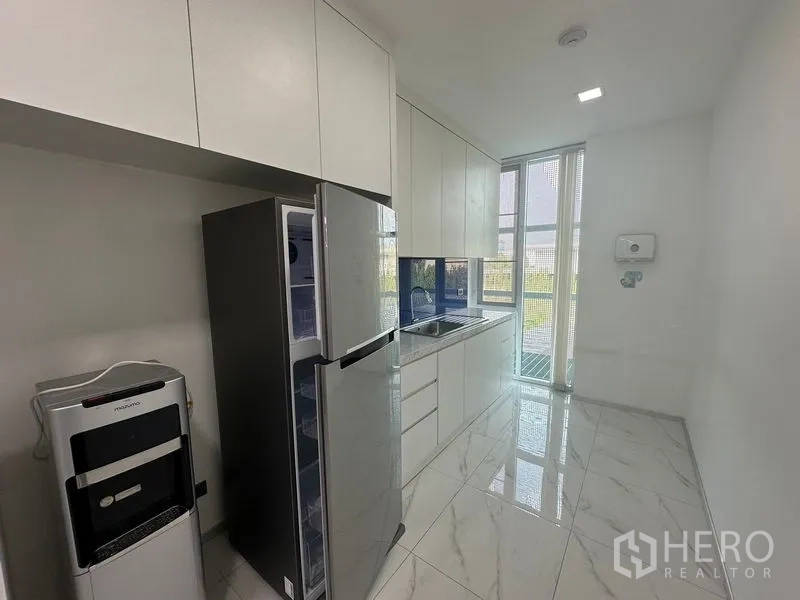 Office Space for rent - Staff pantry with white cabinetry, stainless refrigerator, sink and tall window.