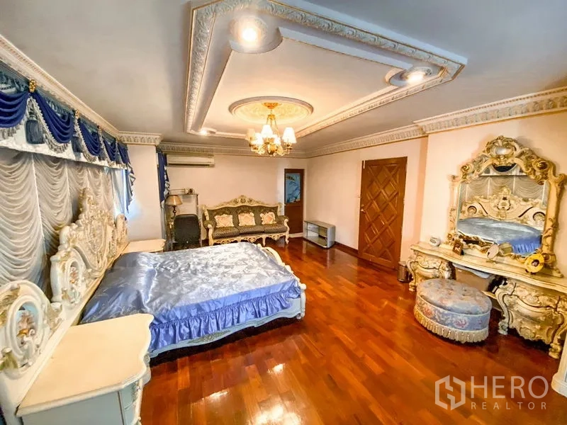 独立式住宅 出租或出售在Bang Khen, Bangkok - 卧室另一角度，蓝色帘幔、雕花梳妆台与吊灯。