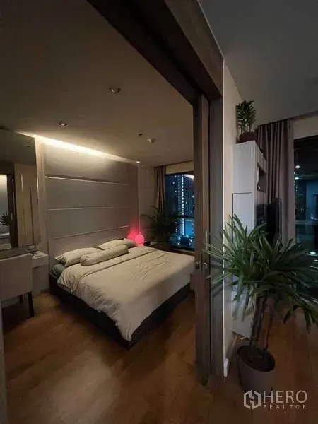 公寓 出租在Bang Rak, Bangkok - 卧室与起居区相连，暖色灯光与室内绿植