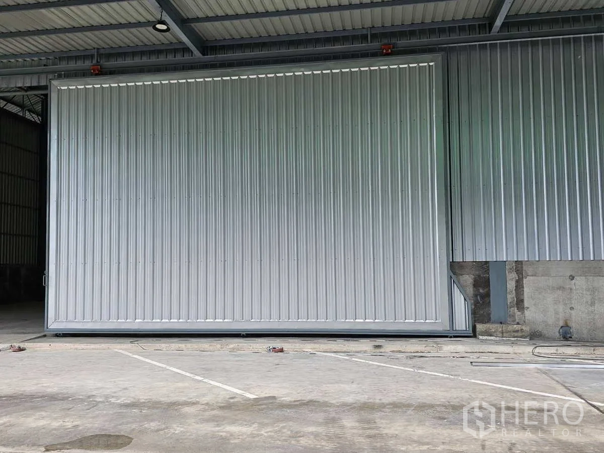 คลังสินค้า ให้เช่าในLam Luk Ka, Pathum Thani - ภาพระยะใกล้ของประตูบานเลื่อนสีเทาขนาดใหญ่ทางเข้าโกดัง