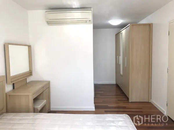 Condominium for rent in Watthana, Bangkok - Bedroom view with air conditioner, full-height wardrobe and wood flooring.
