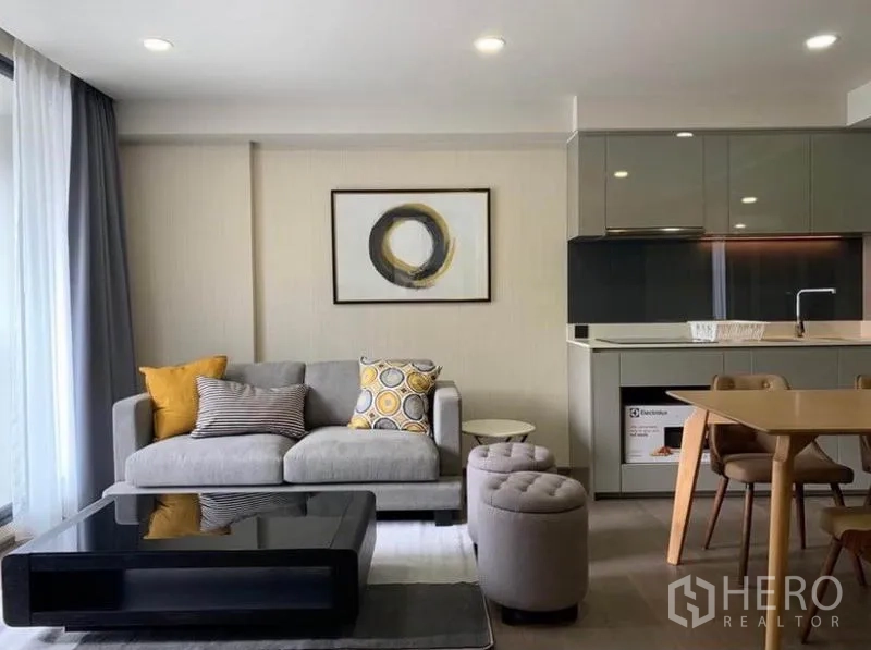 คอนโด ให้เช่าในPathum Wan, Bangkok - ห้องนั่งเล่นแบบเปิดโล่ง โซฟาสีเทา โต๊ะกลาง และครัวขนาดกะทัดรัดตู้บิวท์อินเงางาม