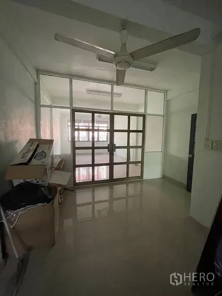 Shophouse for sale in Sathon, Bangkok - Compact office room with ceiling fan and framed glass partition doors.