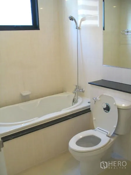 Condominium for rent in Watthana, Bangkok - Bathroom with bathtub, handheld shower, toilet, and window.
