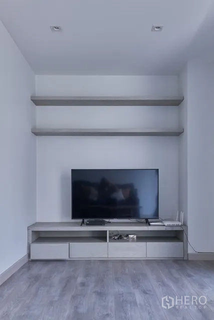 联排别墅 出租在Watthana, Bangkok - 电视背景墙带悬空层板与低柜的影音角。