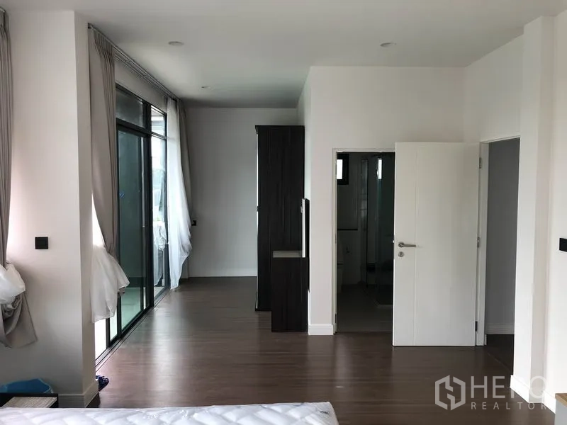 Detached House for rent or sale in Bang Kapi, Bangkok - Master suite corridor leading to balcony and ensuite, with wood floors and wardrobes.