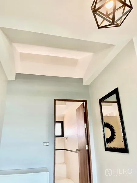 Townhouse for rent in Khlong Toei, Bangkok - Bright hallway with geometric pendant light, wall mirror, and doorway to a bathroom in a modern townhouse.