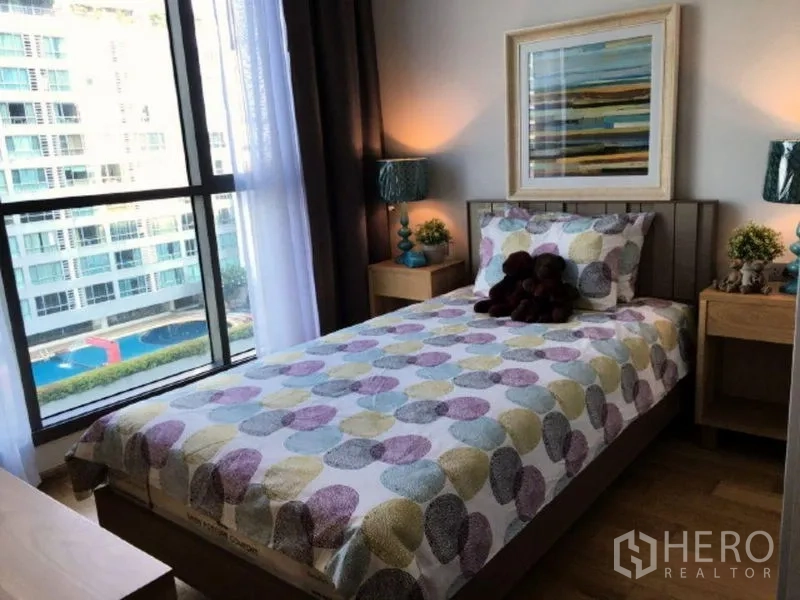 คอนโด ให้เช่าในWatthana, Bangkok - ห้องนอนรองเตียงเดี่ยว โต๊ะข้างเตียง และหน้าต่างบานใหญ่เห็นวิวสระว่ายน้ำและเมือง