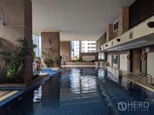 Condominium for rent in Watthana, Bangkok - Covered swimming pool with blue tile deck and city outlook in a high-rise condo.