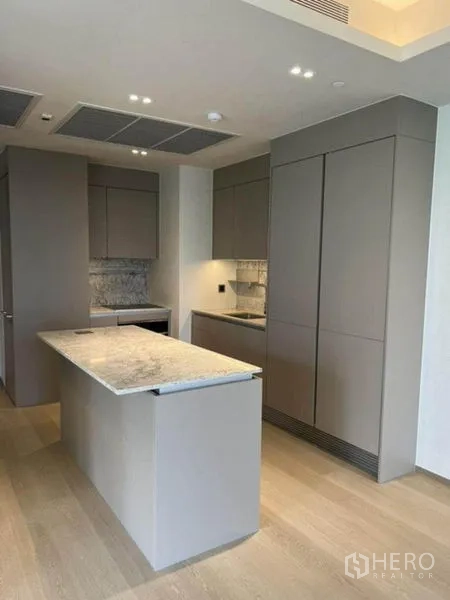 Condominium for rent in Pathum Wan, Bangkok - Full kitchen view with island, tall pantry cabinets and wood flooring.