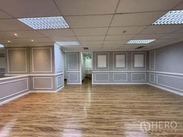 Office Space for rent - Spacious office interior with wood-look flooring, decorative wall panels and grid ceiling lights.