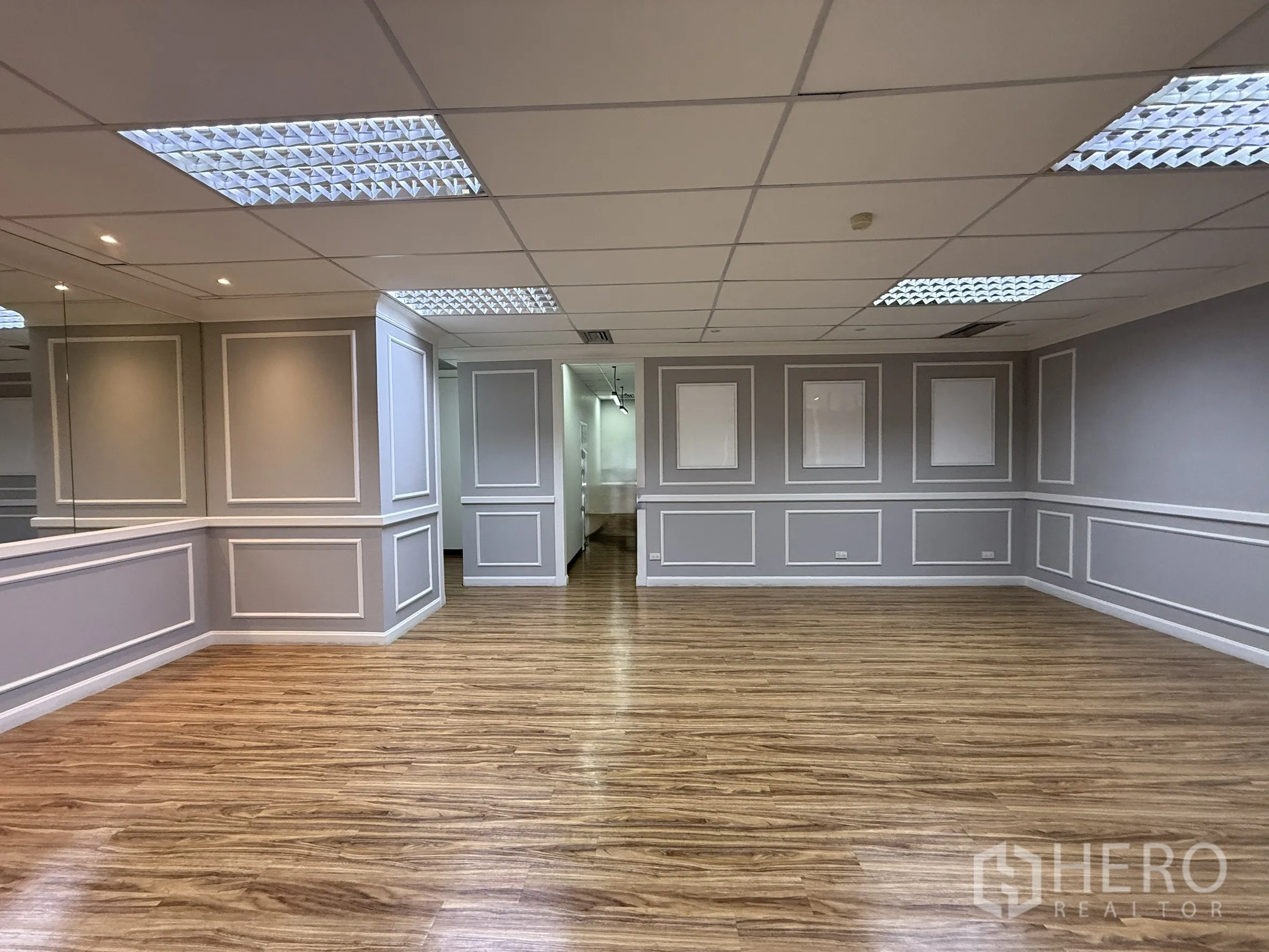 Office Space for rent - Spacious office interior with wood-look flooring, decorative wall panels and grid ceiling lights.