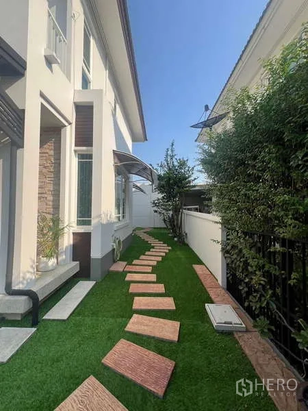 บ้าน ให้เช่าในBang Kapi, Bangkok - สวนข้างบ้านพร้อมทางเดินแผ่นทางตามแนวบานบ้านและรั้วบังสายตา